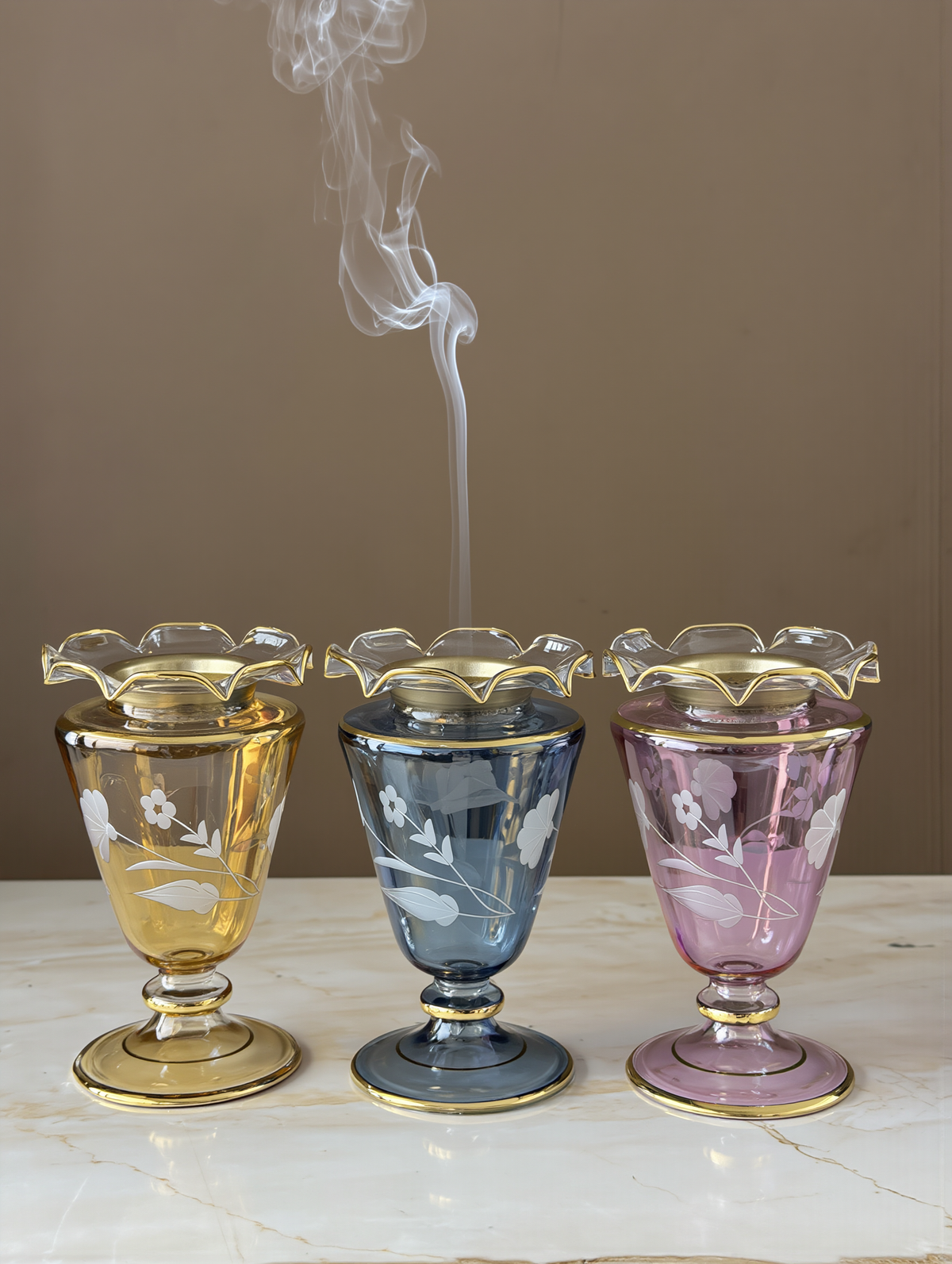 Matching mini glass mabakhir in one colour set along a table for guests