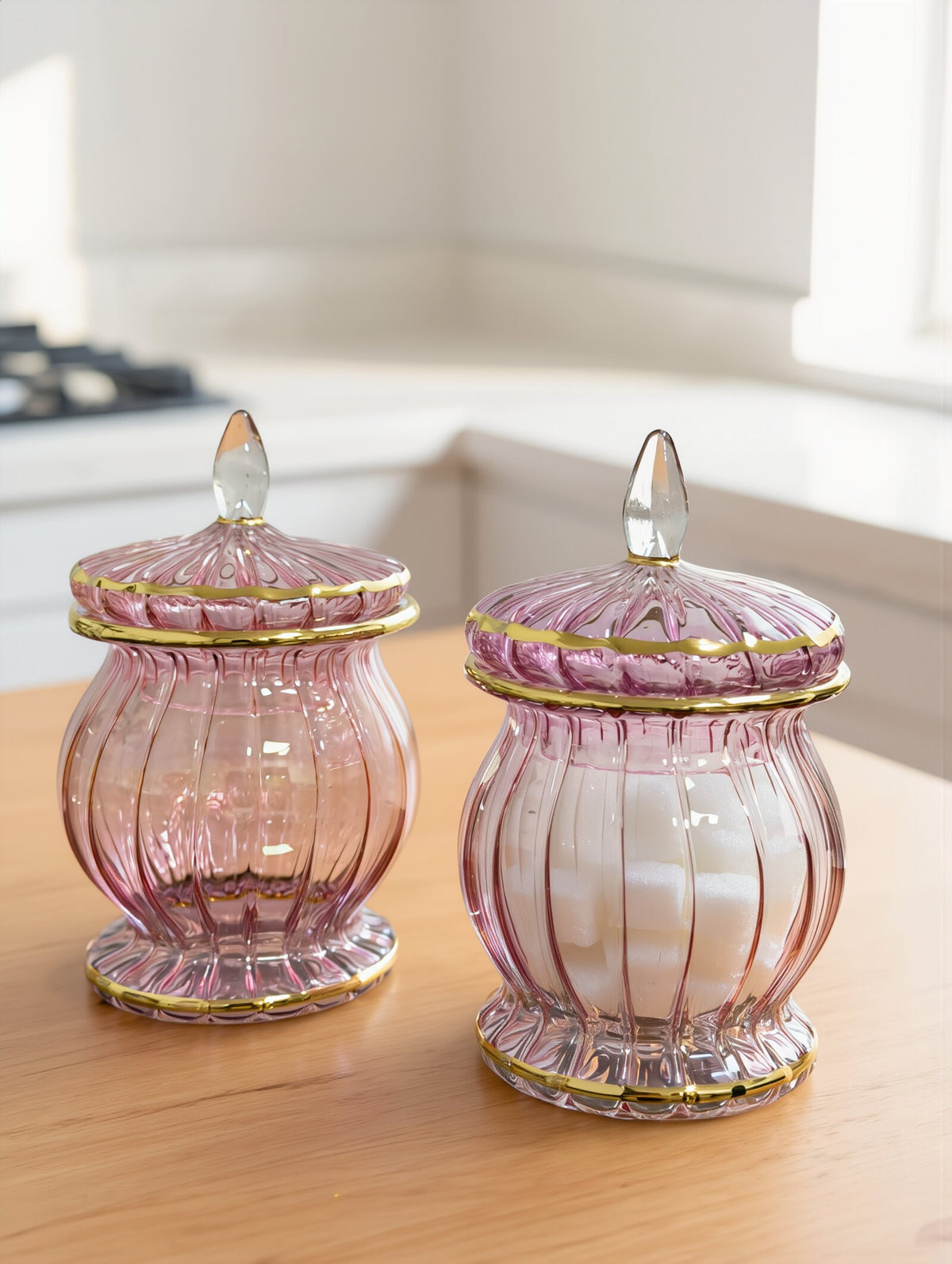 Pair of rose pink Egyptian glass candy jars with gold rims and teardrop finials