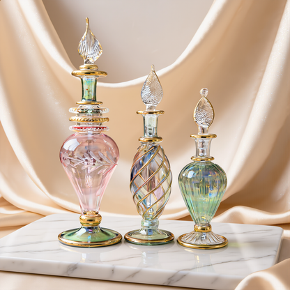 Three mini hand-blown Egyptian glass perfume bottles in pastel colours on ivory satin