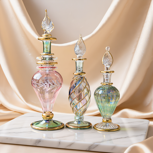 Three mini hand-blown Egyptian glass perfume bottles in pastel colours on ivory satin