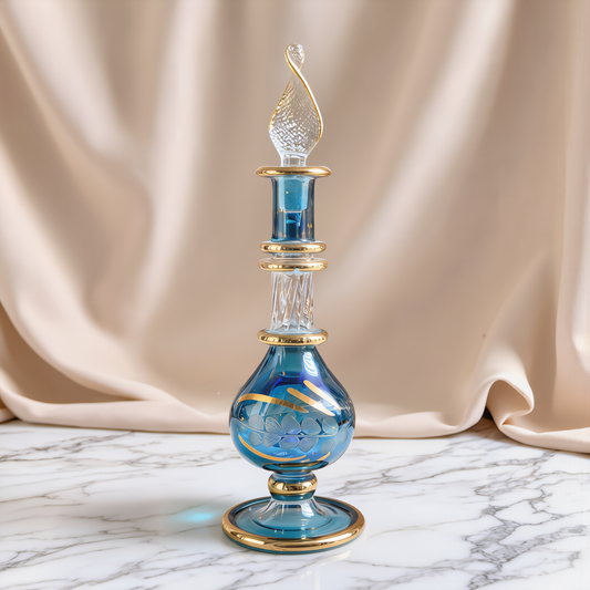 Small blue Egyptian glass perfume bottle with gold rim on marble beside satin