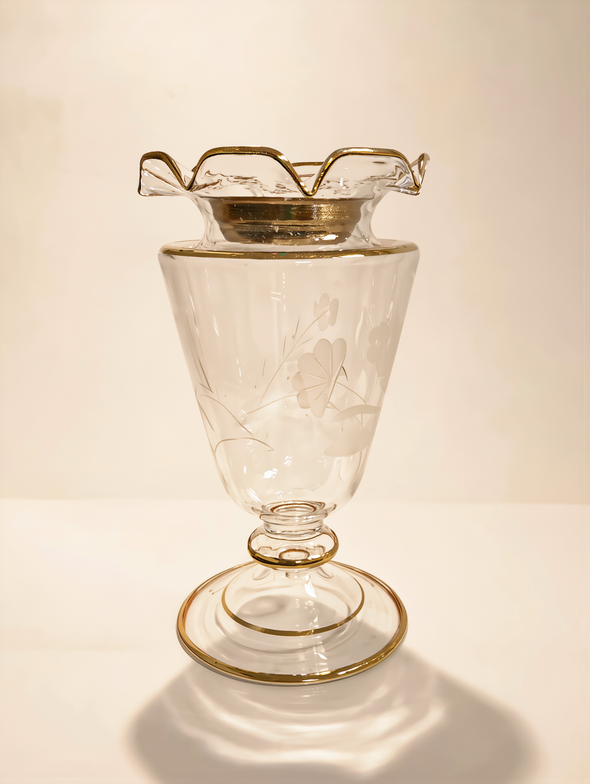 Clear hand-blown Egyptian glass mabkhara with gold ruffled rim on a beige studio background