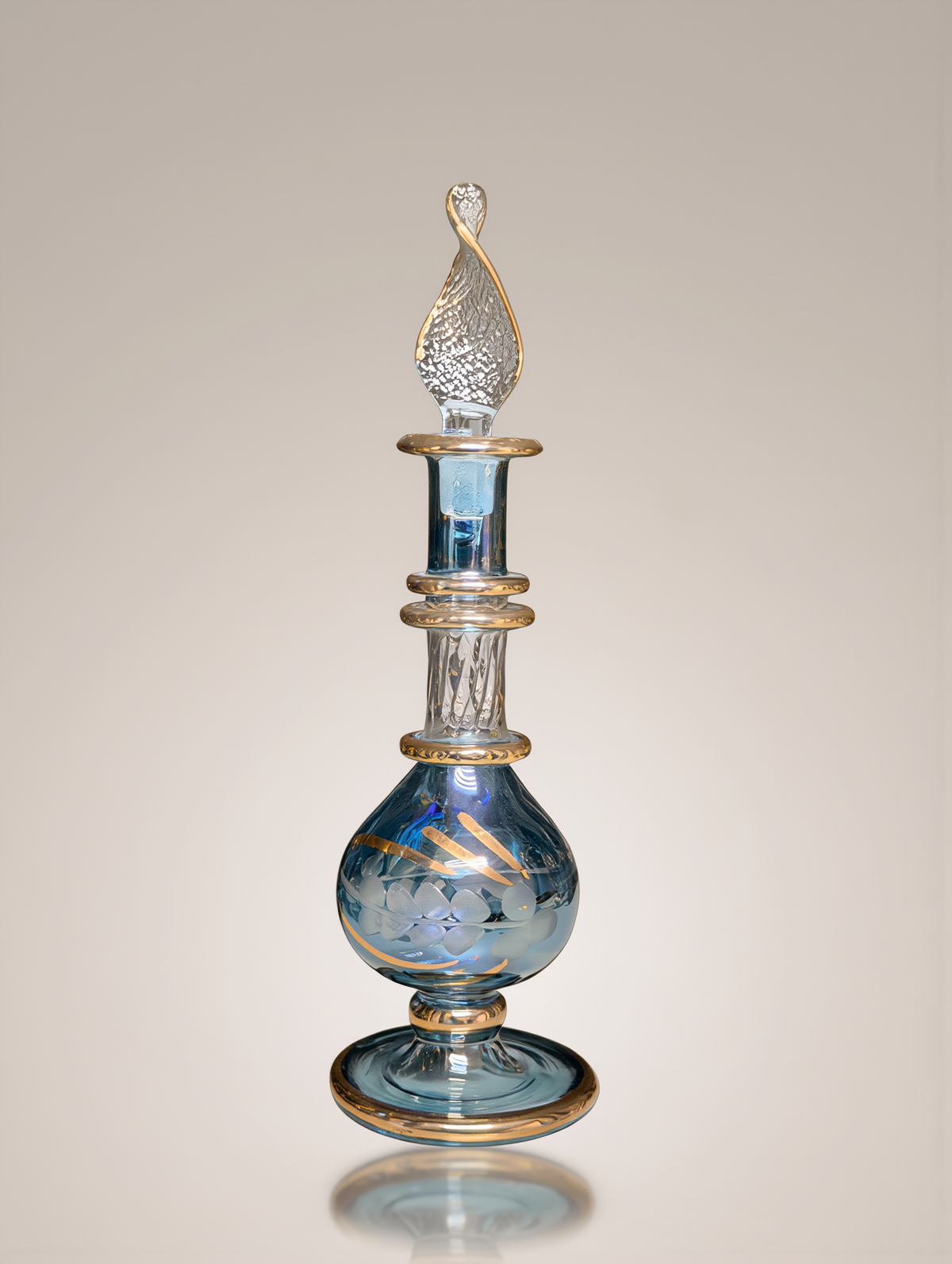 Blue Egyptian glass perfume bottle with gold trim in a studio setting