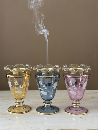 Matching mini glass mabakhir in one colour set along a table for guests